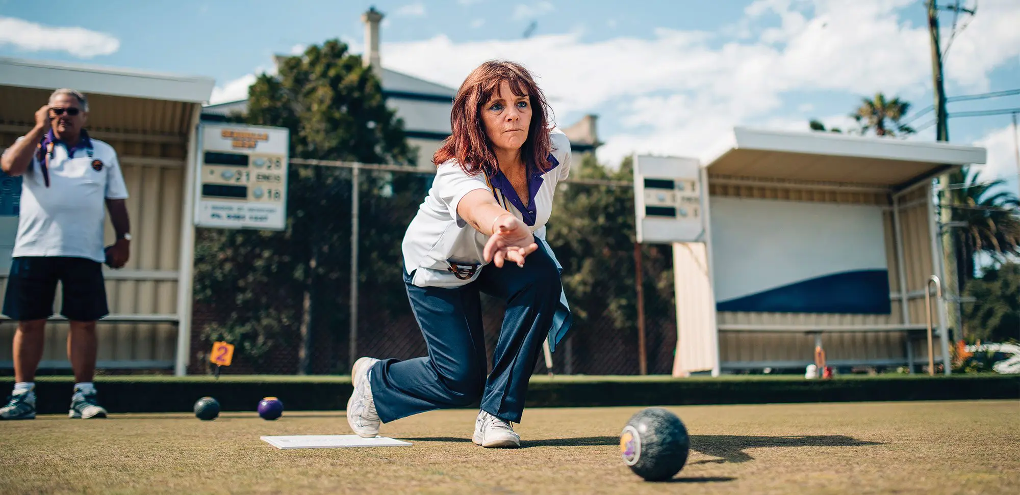 Action shot of mature woman lawn bowling.