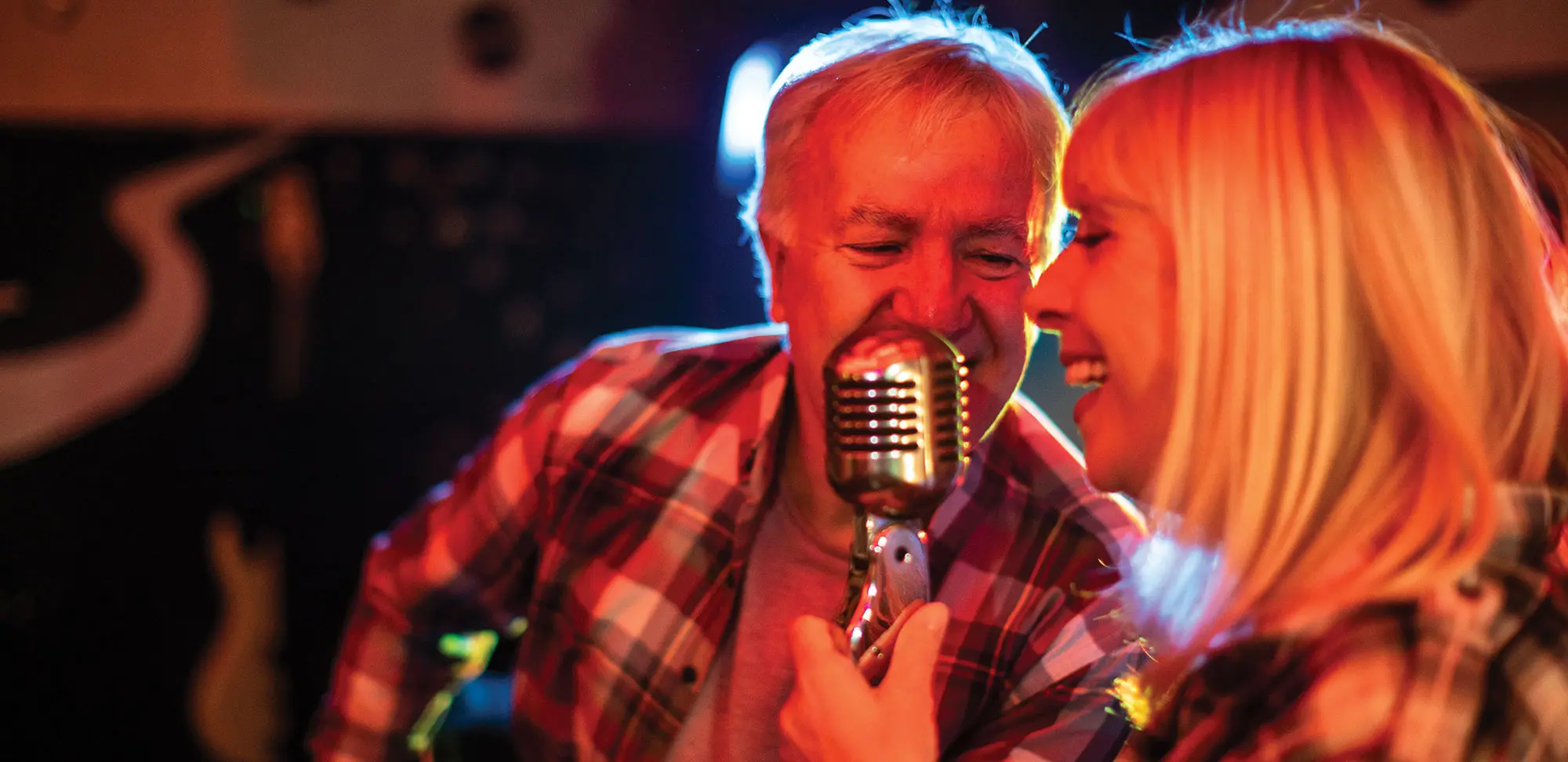 Photo de deux musiciens d’un groupe chantant ensemble sur scène lors d’un concert