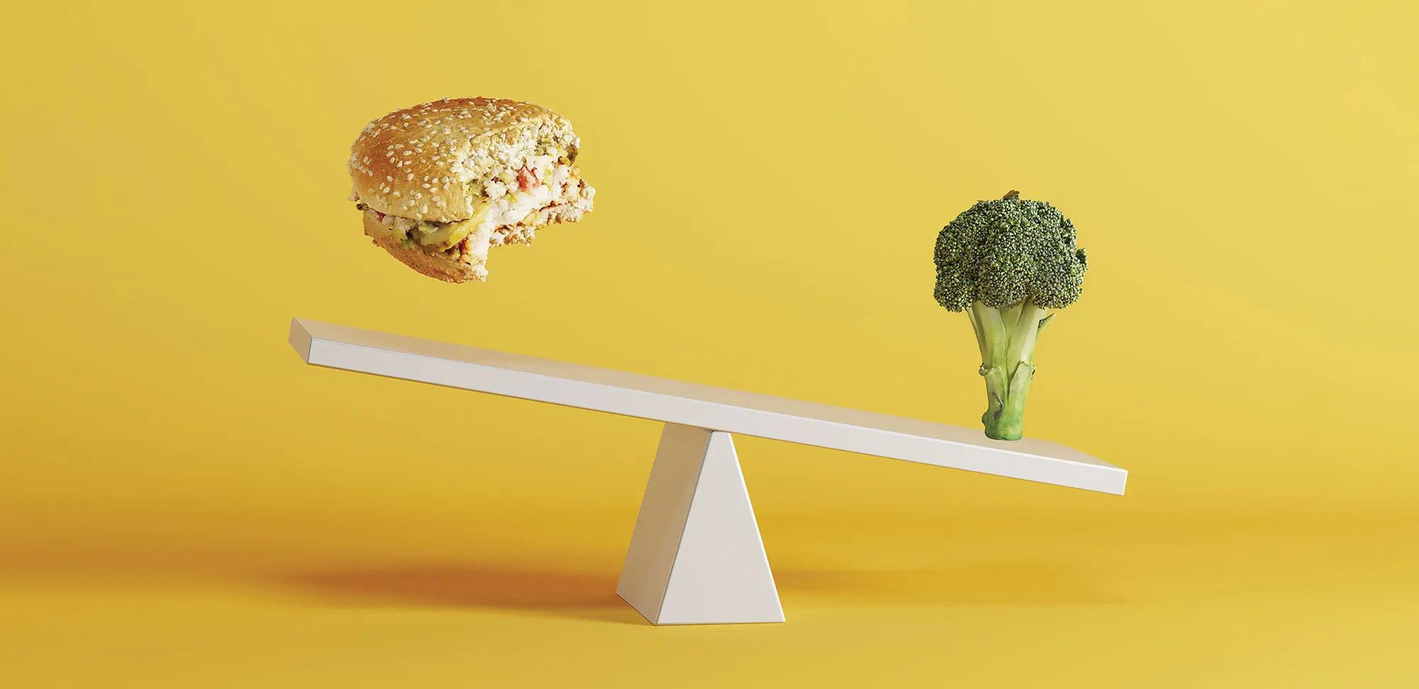 Photo of broccoli vegetable tipping seesaw with floating berger on opposite end on yellow background.