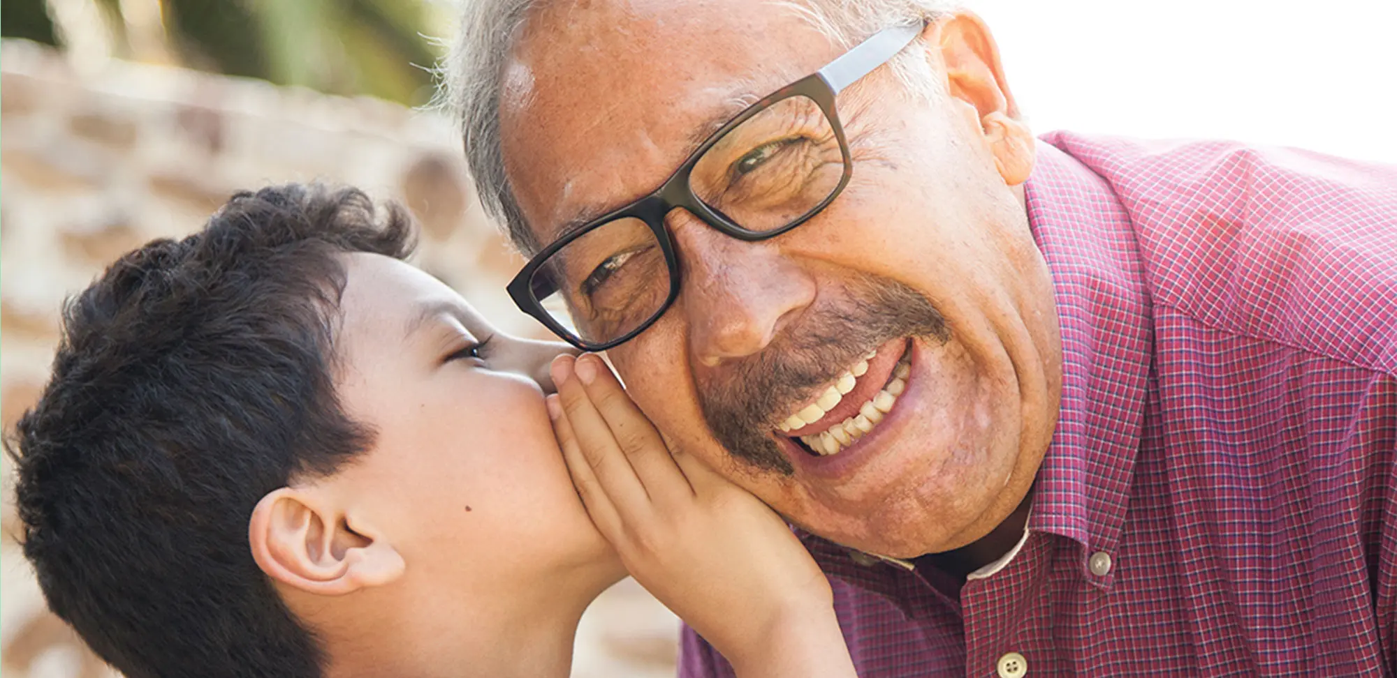 Photo of little boy whispering to grandpa