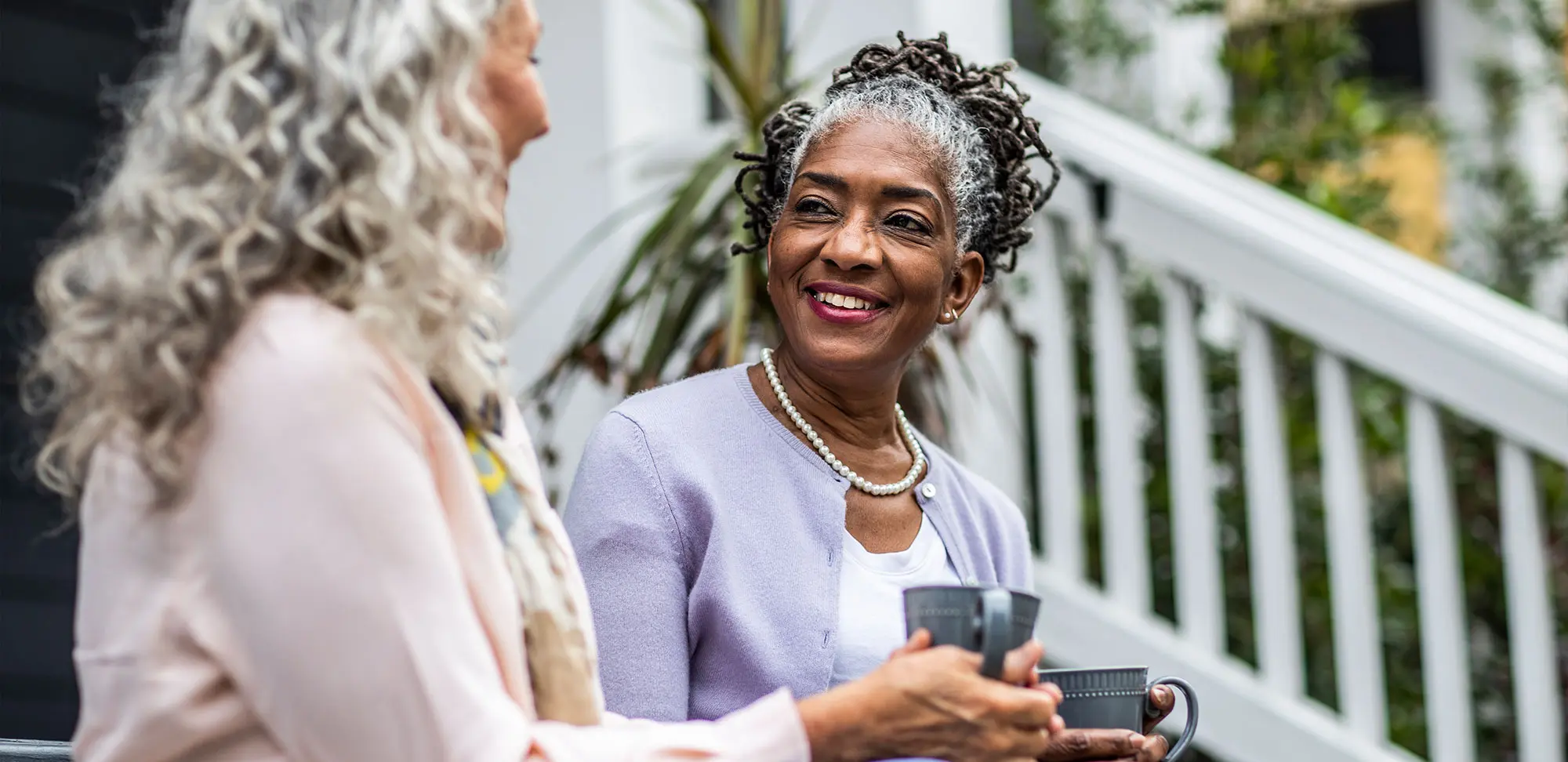 Photo of Senior women having coffee in front of suburban home