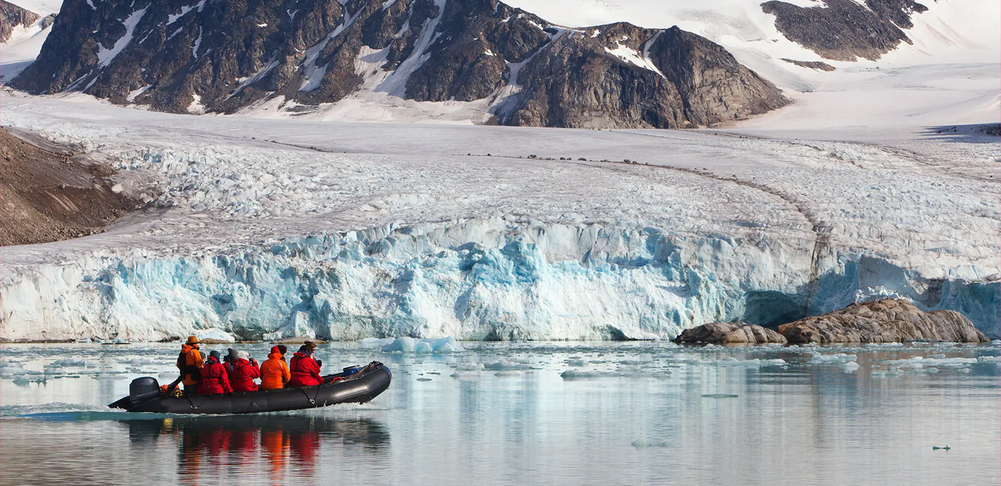 Photo de touristes en croisière lors d’une expédition polaire en bateau Zodiak dans des baies glacées