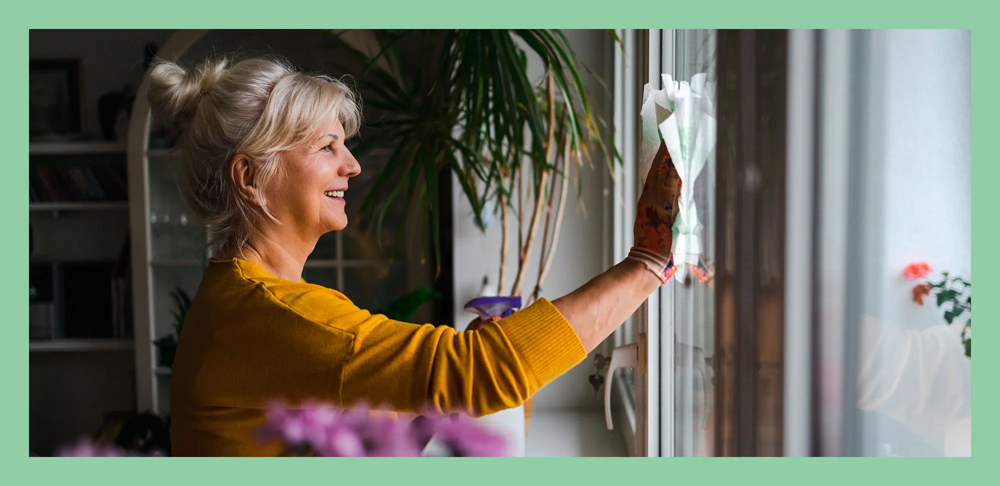 Photo d’une femme âgée nettoyant les vitres de sa maison