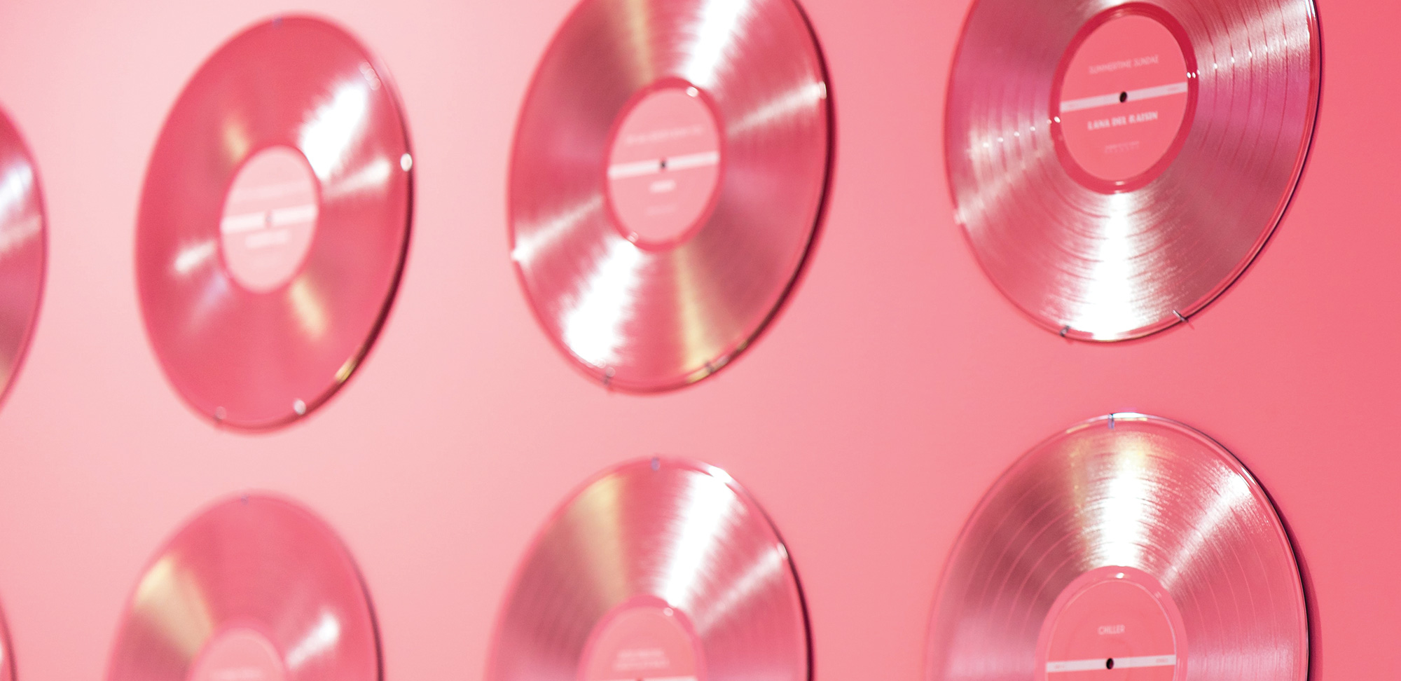 Photo de disques vinyles roses sur un mur rose