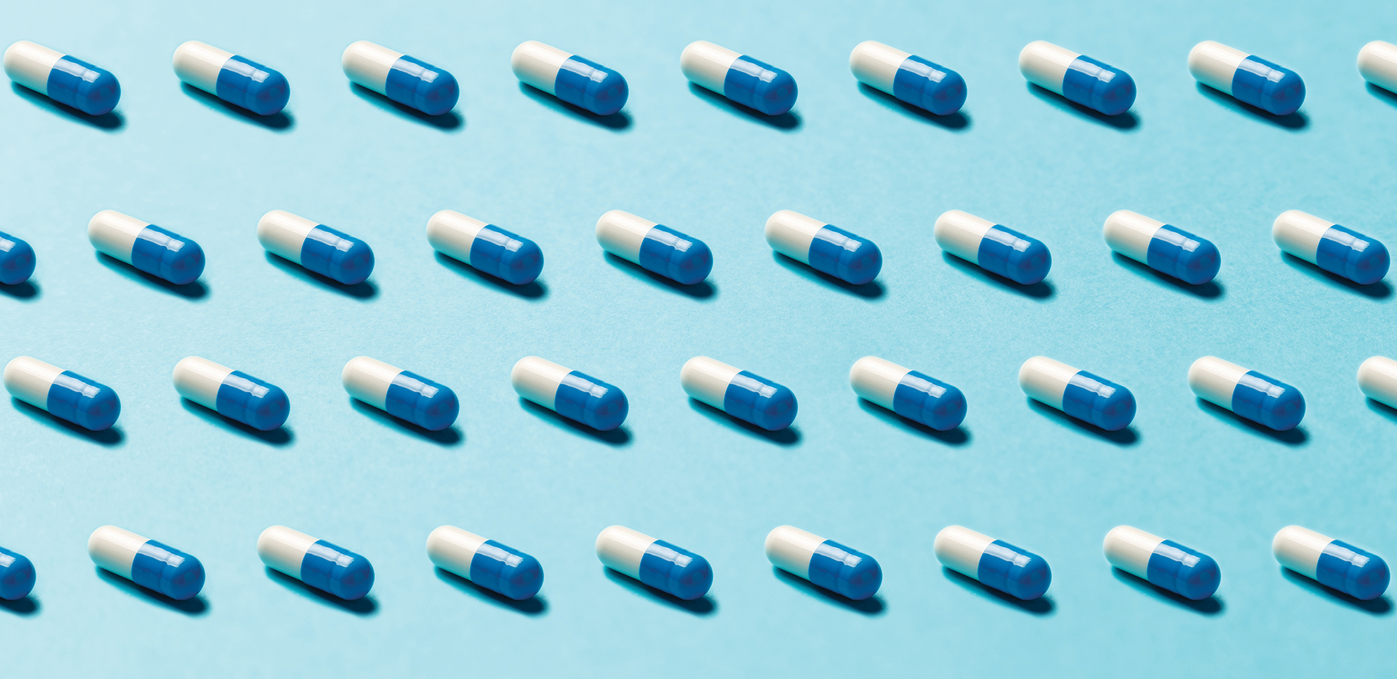 Photo of rows of identical pills on a blue background
