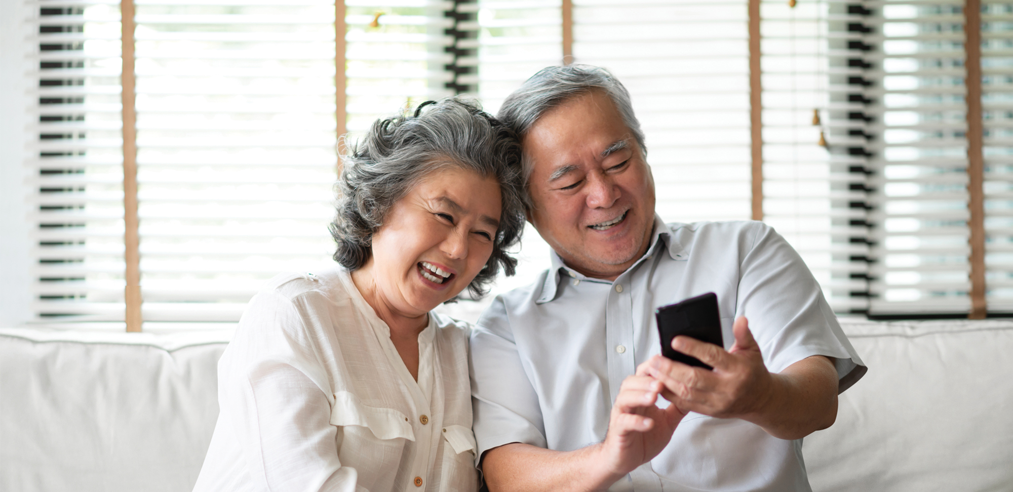Photo of a senior couple enjoying while doing video call via app on phone