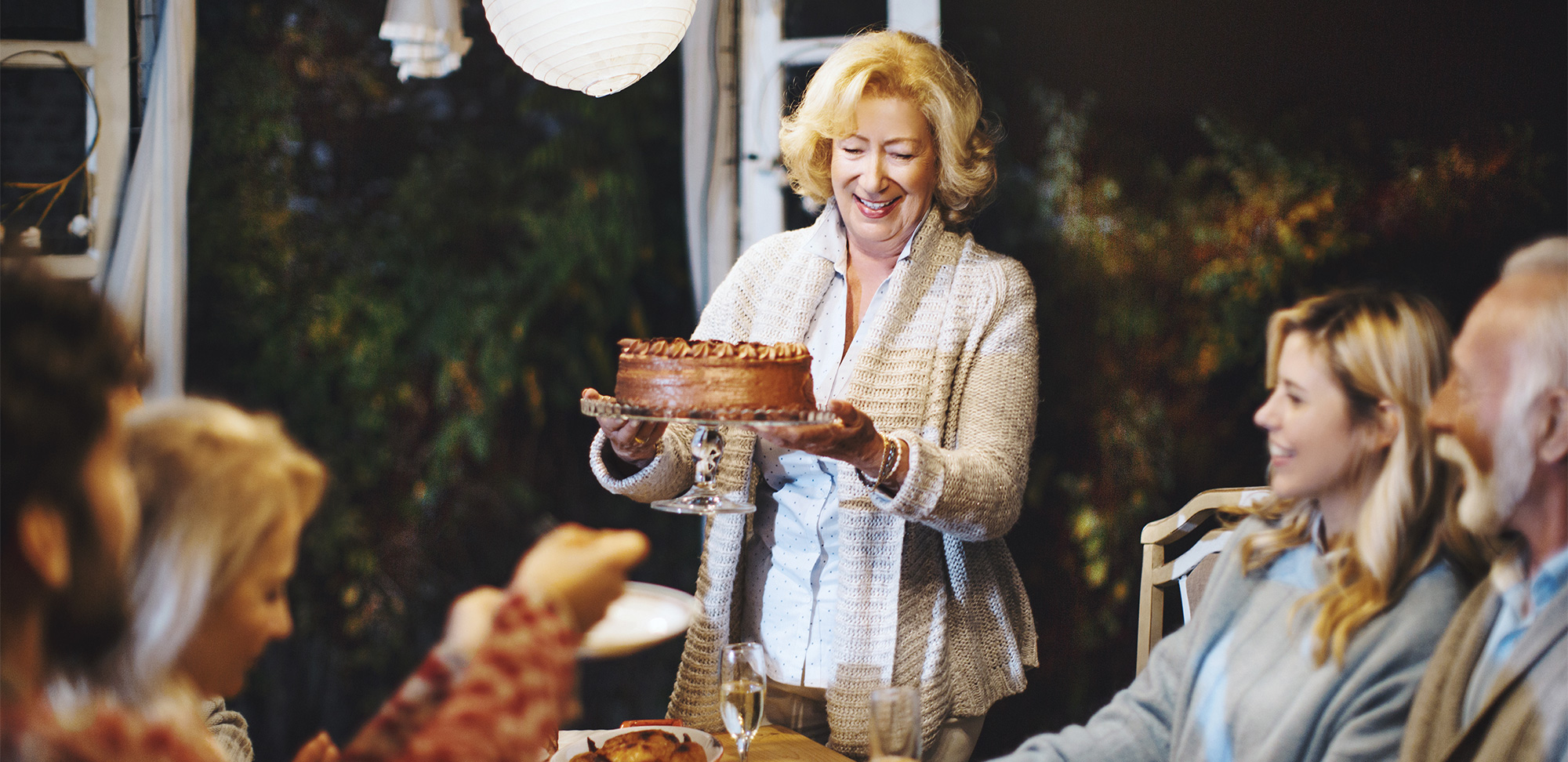 Photo d’une famille célébrant ensemble l’Action de grâce. Femme plus âgée servant un gâteau au chocolat à sa famille.