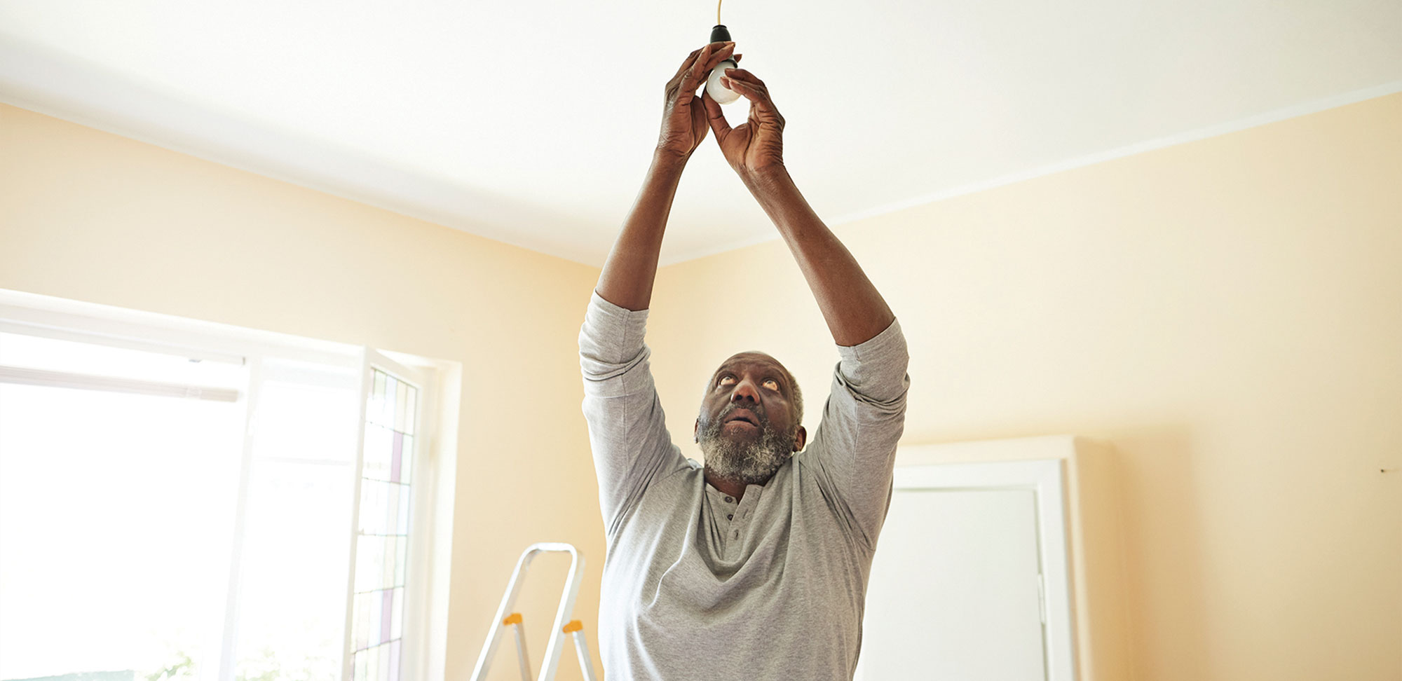 Photo of a Man changing light bulb while renovating home
