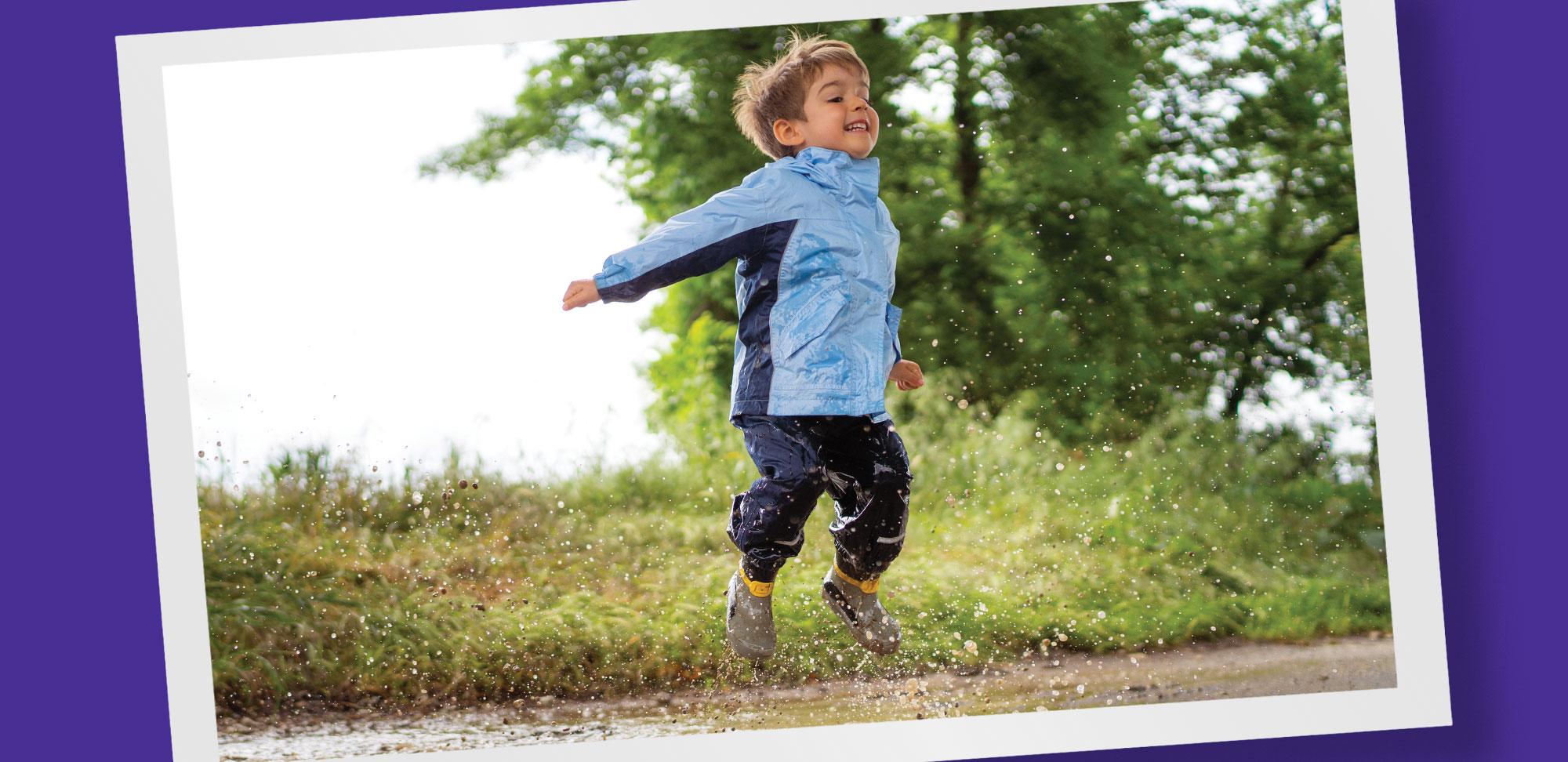 Photo of a boy jumping in a rain puddle